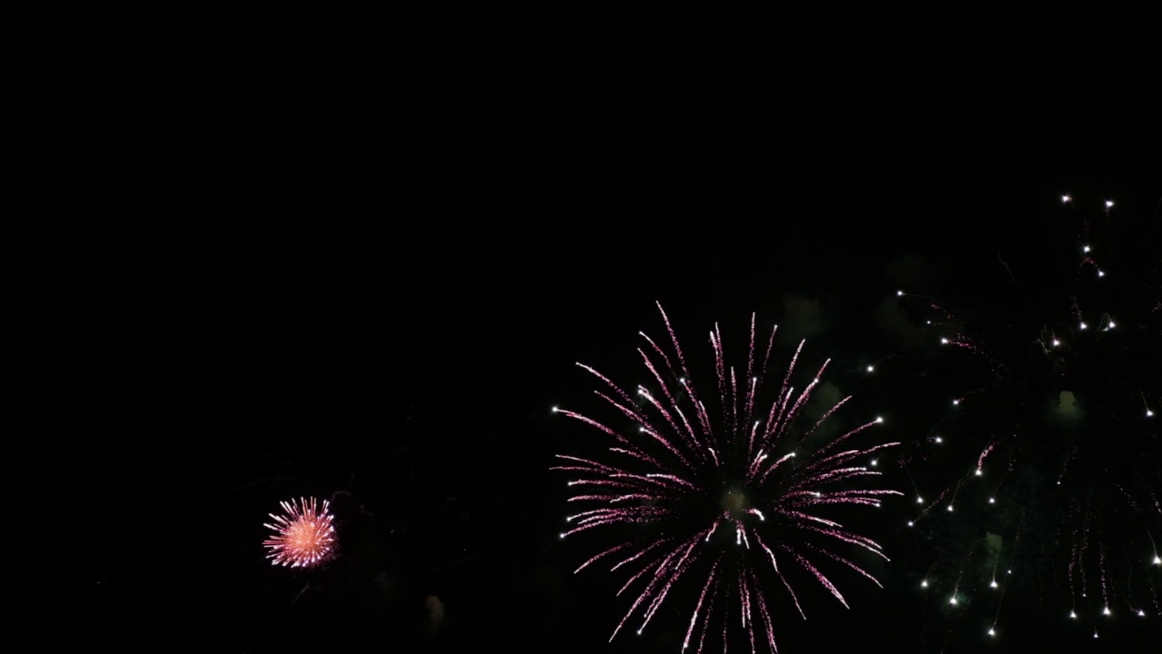 烟花的背景。一个真实的彩色闪耀的烟花与灯光在夜空的抽象图像。闪亮的烟花表演。除夕夜的烟火庆祝活动。视频素材