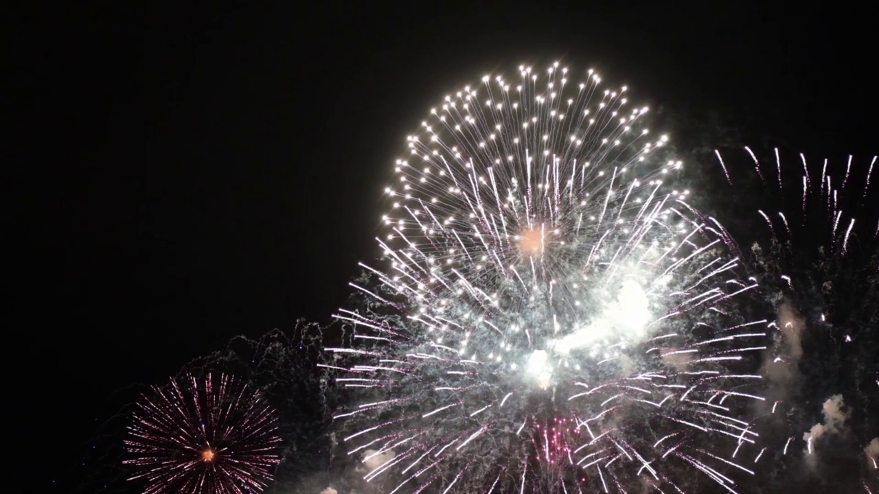 烟花的背景。一个真实的彩色闪耀的烟花与灯光在夜空的抽象图像。闪亮的烟花表演。除夕夜的烟火庆祝活动。视频素材