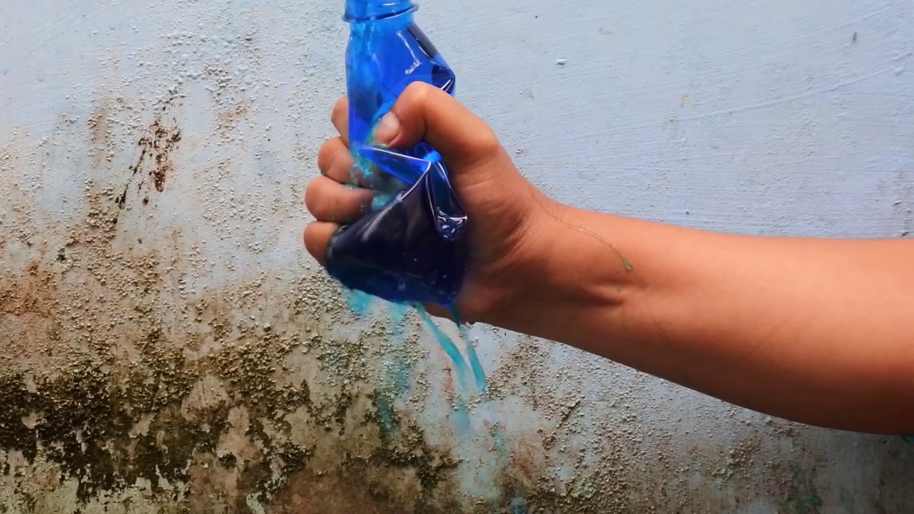 用手挤压装满彩色液体的瓶子，直到它以慢动作喷出。高清视频。视频下载