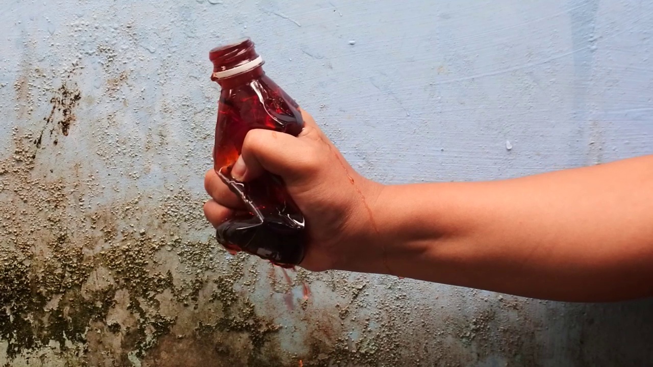 用手挤压装满彩色液体的瓶子，直到它以慢动作喷出。高清视频。视频下载