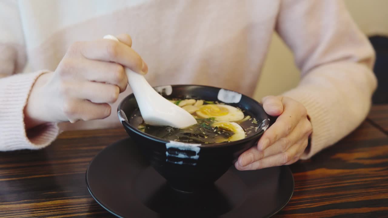 一个女孩在日本餐厅吃鸡肉味增汤。吃亚洲食物的特写镜头。视频素材