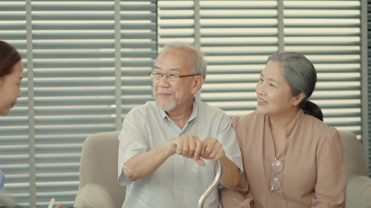 亚洲女医生或护士提供护理支持，与老年夫妇谈论治疗后的病情改善和康复过程。医生向老年患者解释药物测试结果。医院保健退休的概念视频素材