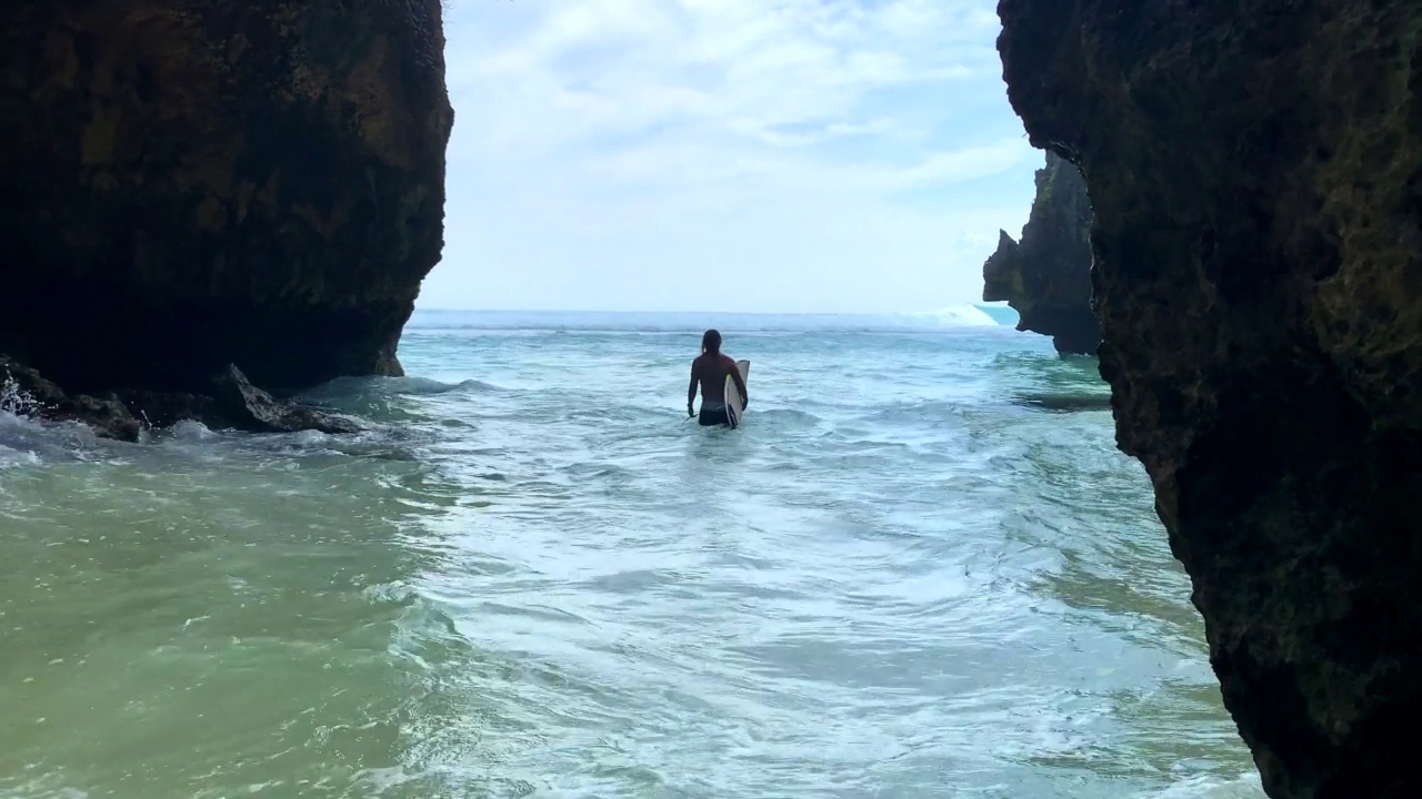 冲浪者的剪影正穿过Uluwatu洞穴，前往巴厘岛的标志性海浪视频素材