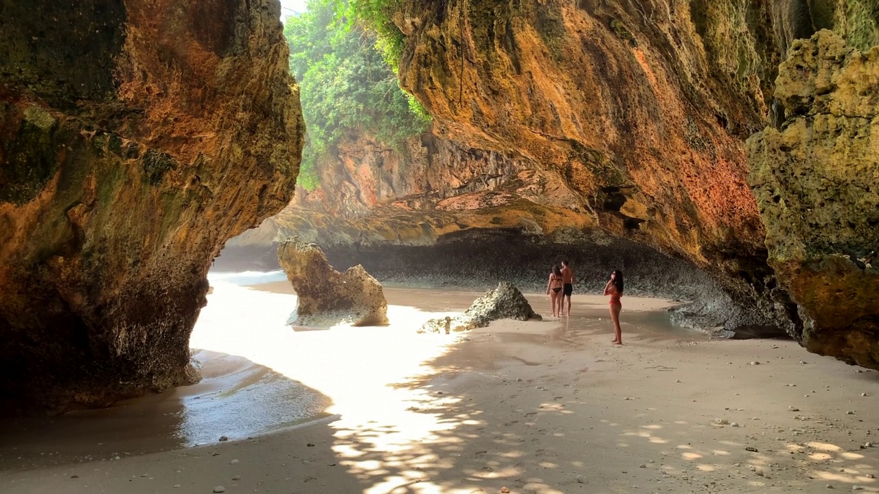 游客和冲浪者在Uluwatu洞穴冲浪者用来到达巴厘岛的标志性海浪视频素材