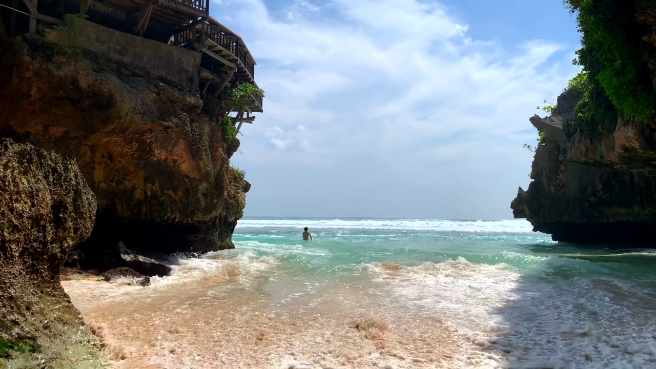 冲浪者正穿过Uluwatu洞穴前往巴厘岛的标志性海浪视频素材