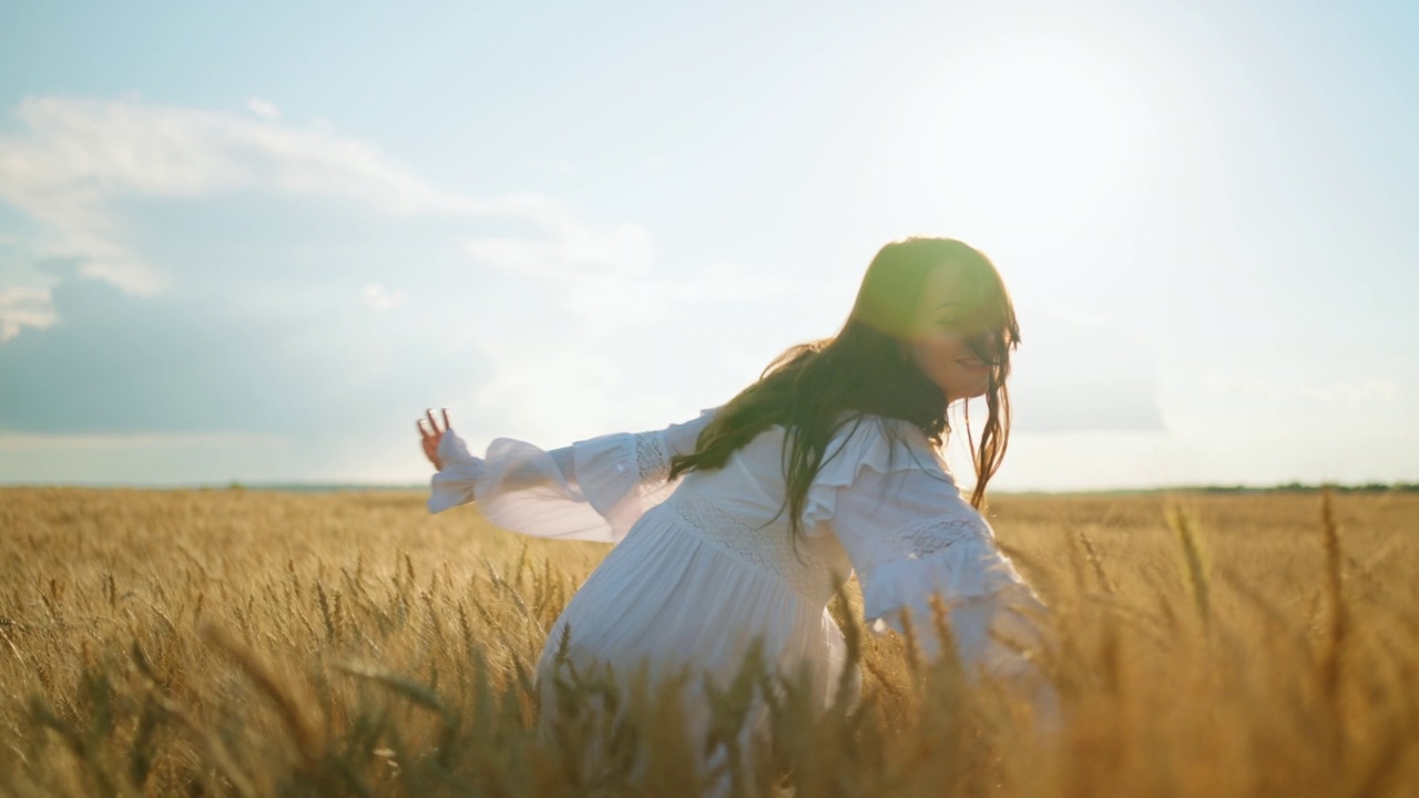 在阳光明媚的夏日里，性感的年轻女子抚摸着农田里金黄的麦穗，幸福快乐视频素材