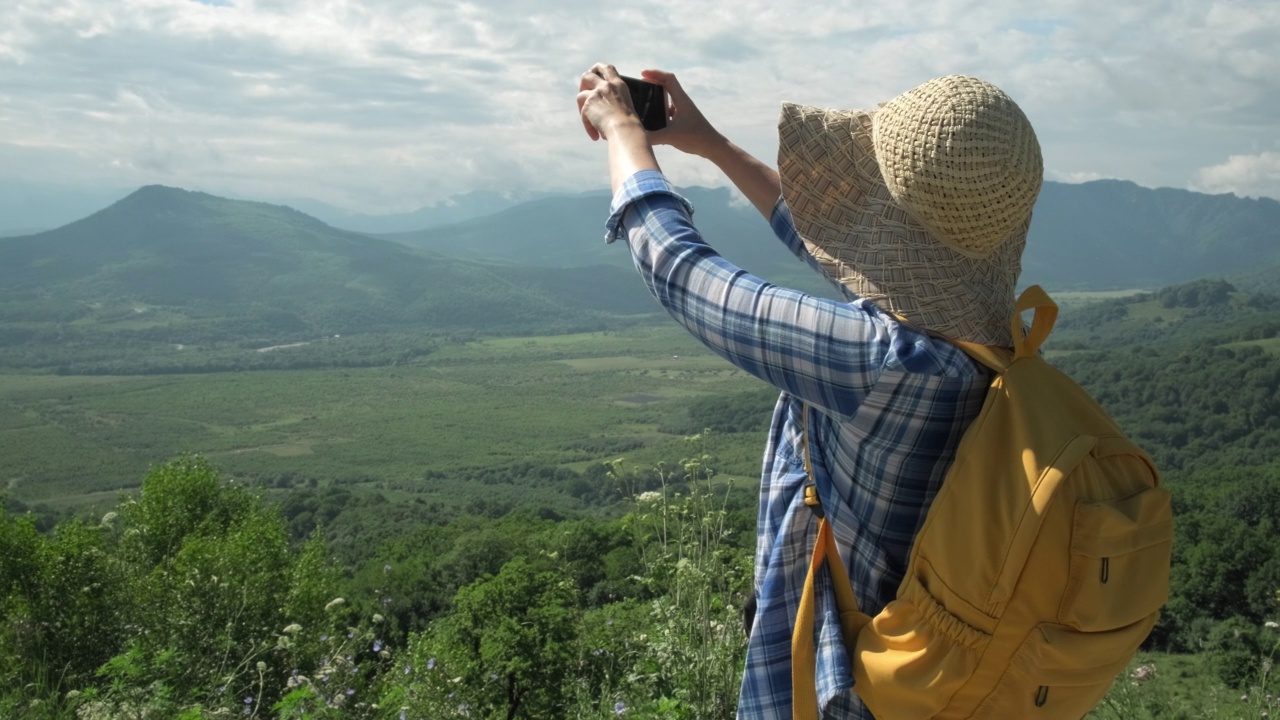 在夏季旅行中，一名女子用手机拍下了山的照片视频素材