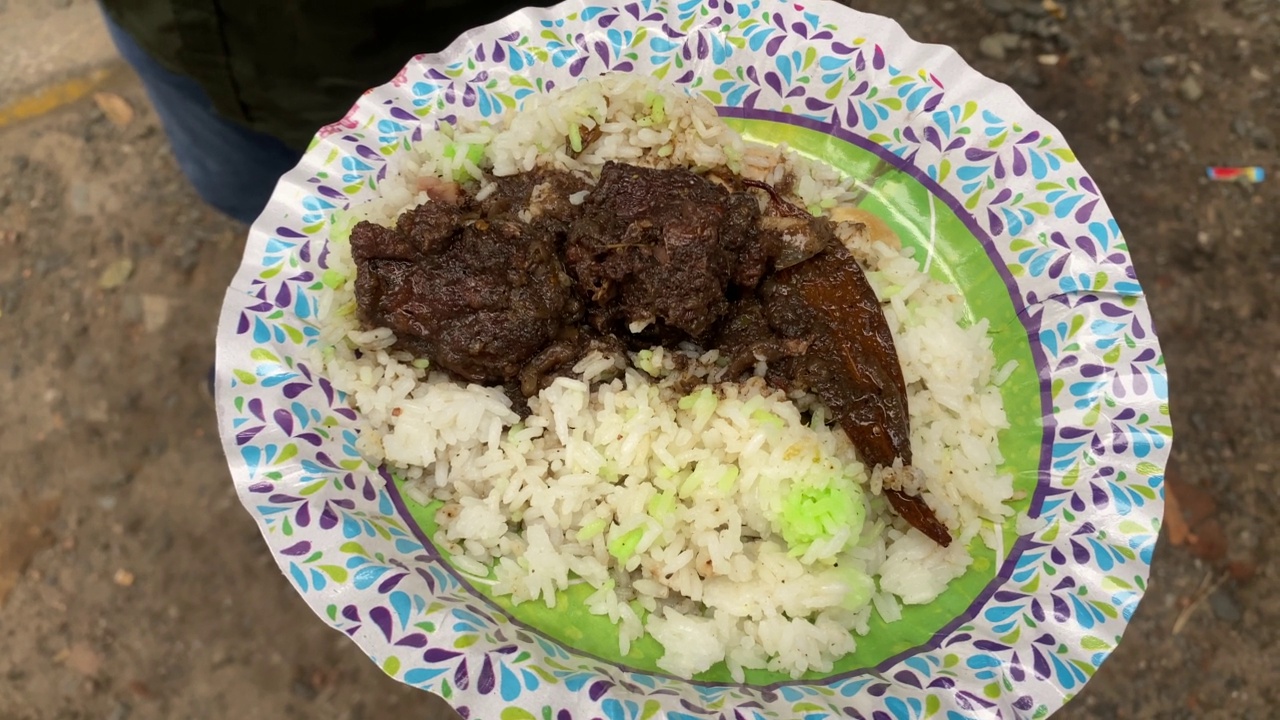 一名男子拿着一盘鸡肉Chusta，用香草和香料慢煮，并用Gondhoraj炒饭调味。视频素材