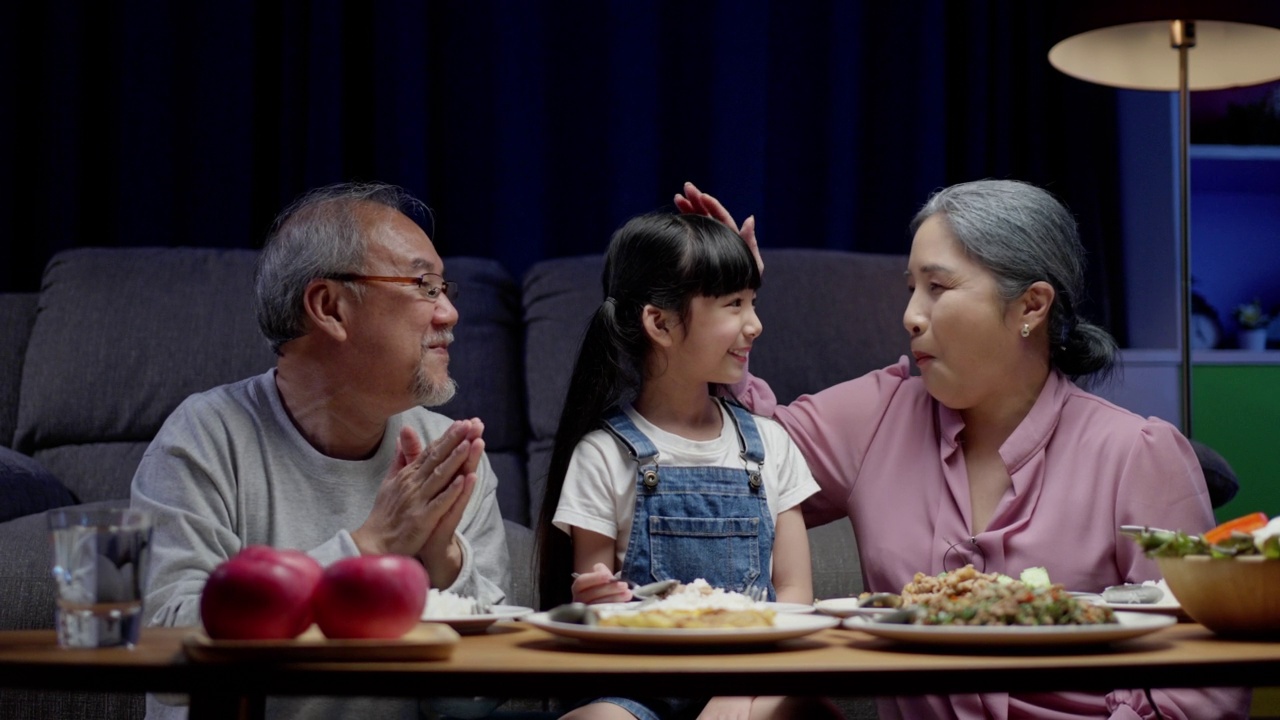 亚洲人幸福的家庭在餐桌上吃午餐，日本人在一起微笑。小孩子女儿喜欢吃爷爷奶奶的食物。幸福时光人们的生活方式观念。视频素材