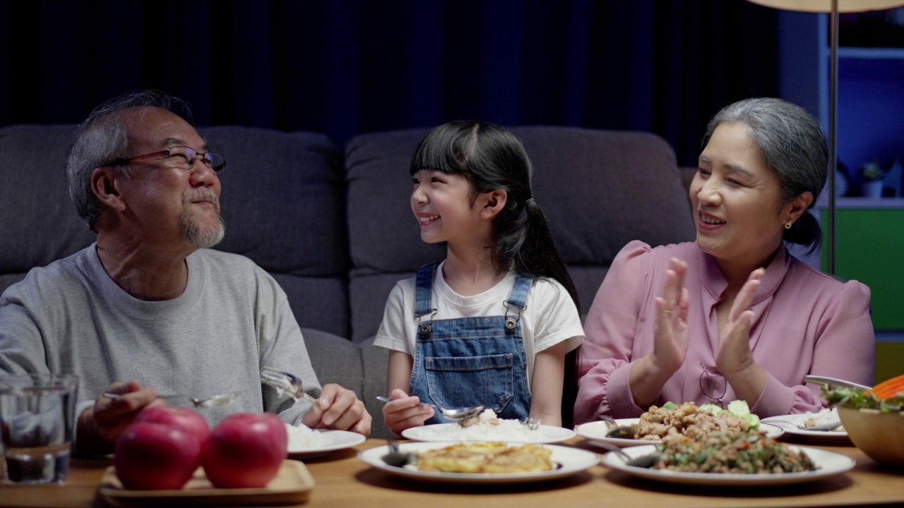 亚洲人幸福的家庭在餐桌上吃午餐，日本人在一起微笑。小孩子女儿喜欢吃爷爷奶奶的食物。幸福时光人们的生活方式观念。视频素材