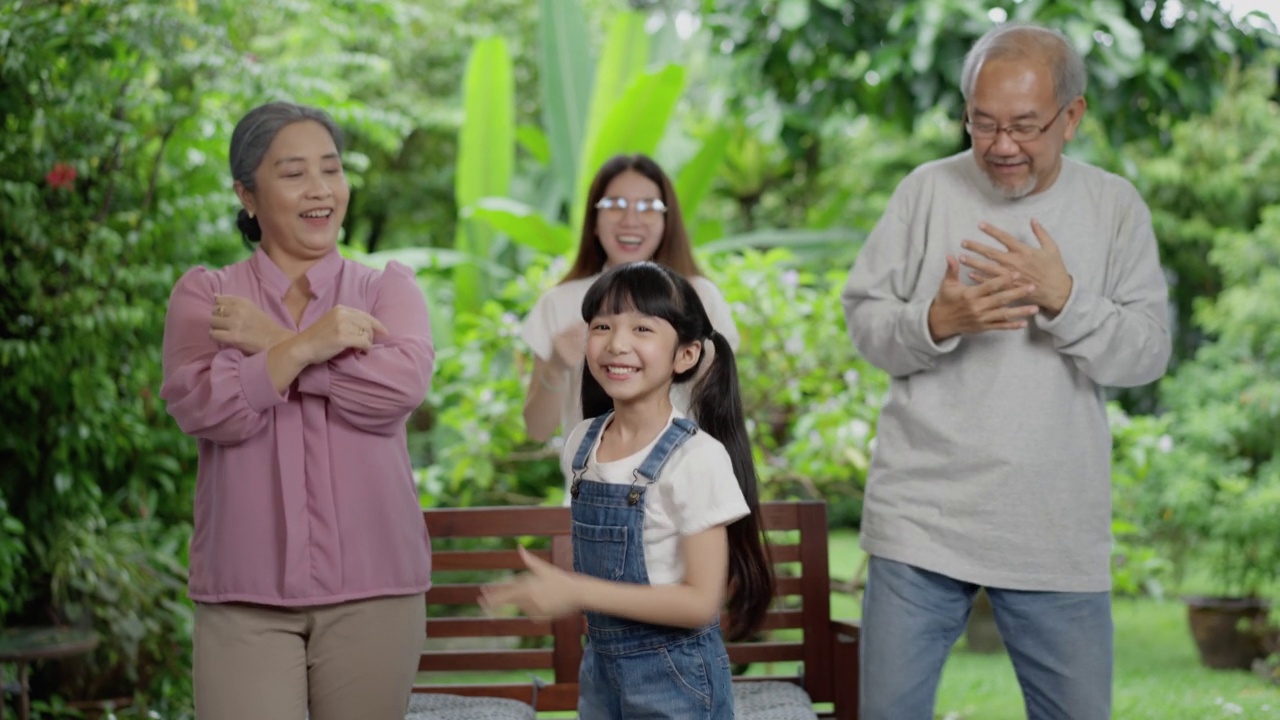 亚洲人的幸福家庭呆在外面
后院。小女孩与爷爷奶奶和妈妈一起跳舞玩耍练习。欢声笑语，在家中享受育儿活动关系。视频素材