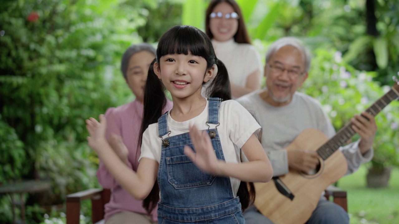 亚洲人的幸福家庭呆在外面
后院。小女孩与爷爷奶奶和妈妈一起跳舞玩耍练习。欢声笑语，在家中享受育儿活动关系。视频素材