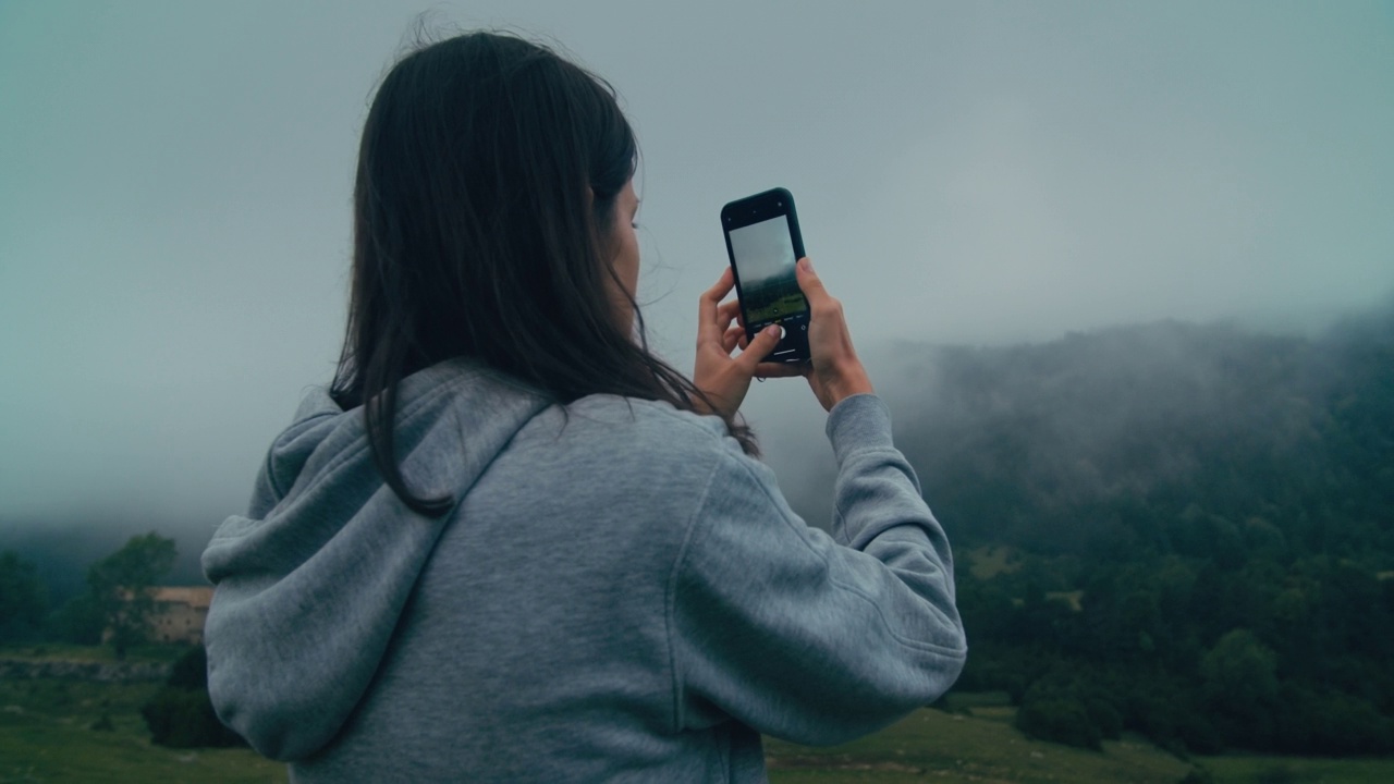 女旅行者用智能手机在山区旅行中拍摄云景视频素材