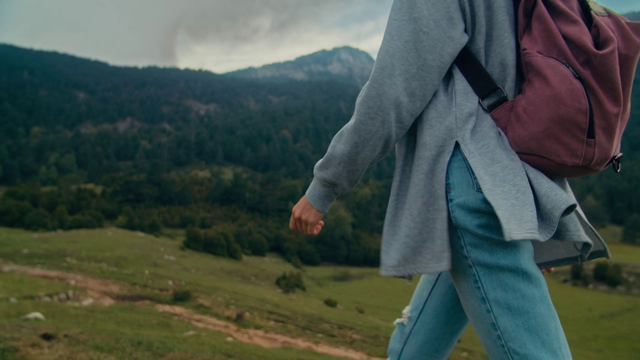 不认识的女人背着背包走在山间草地上度假旅行视频素材