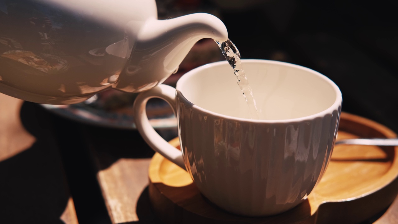 近距离的视频酒保倒橙茶在白色的杯子在城市的户外。视频素材