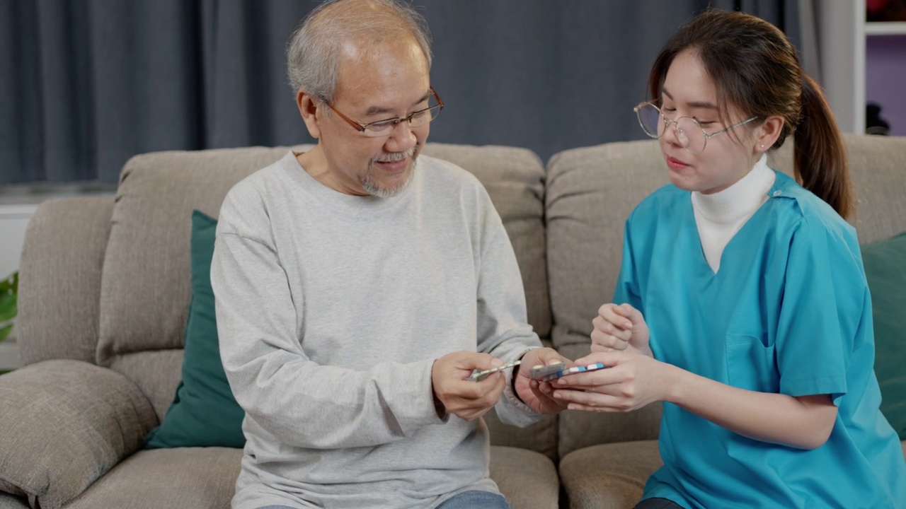 亚洲老年男性患者在敬老院与医生护士咨询处方药。护工治疗师药剂师妇女在客厅里拿着药瓶，药量在家里。视频素材