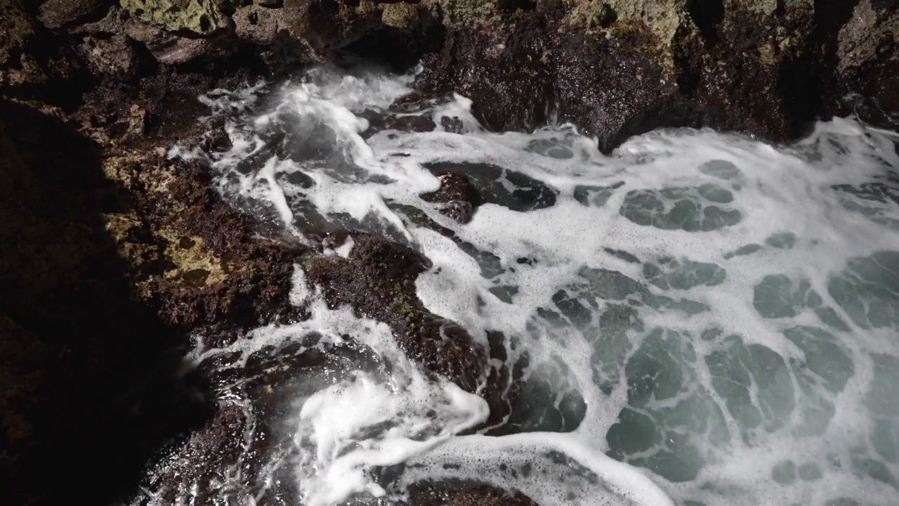 特写的海浪泡沫和破碎的岩石在海岸上。戏剧性的海景视频素材