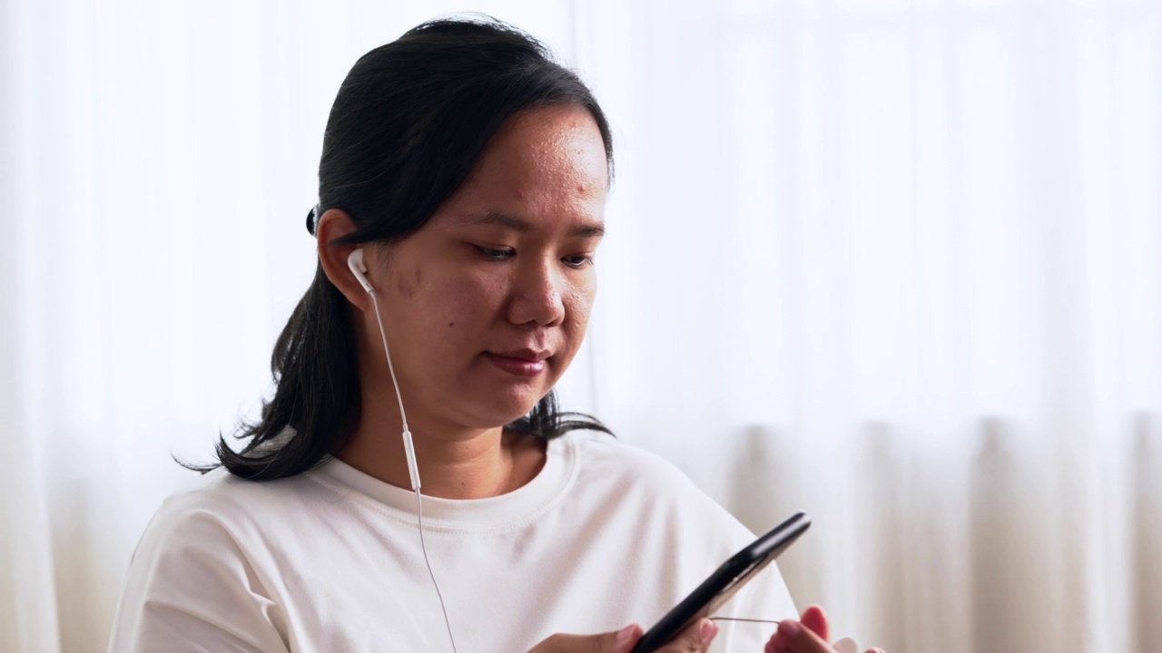 快乐的女人戴着耳机，喜欢用智能手机听音乐视频素材