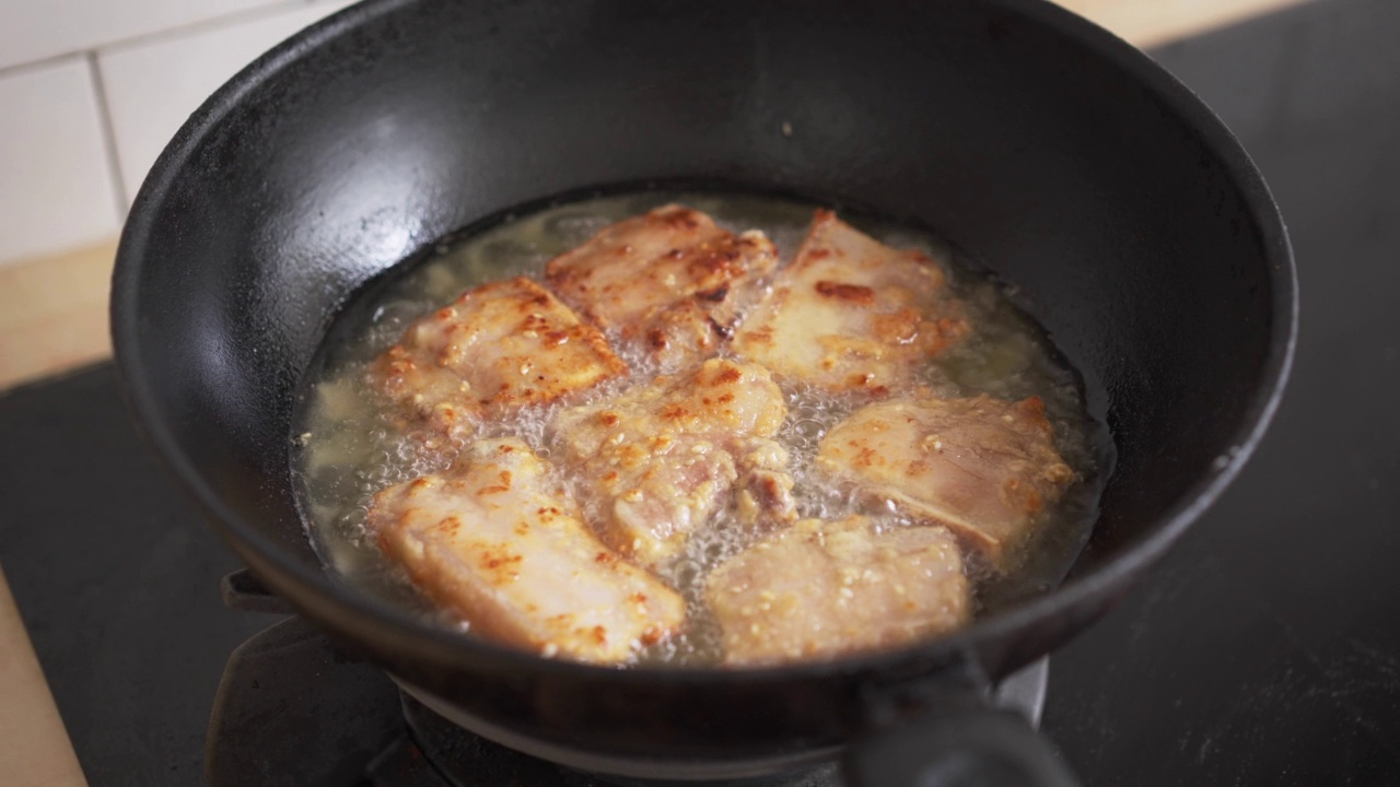 厨房油锅上煎得酥脆的五花肉特写。不健康的亚洲食物高胆固醇，晚餐准备肉类视频素材