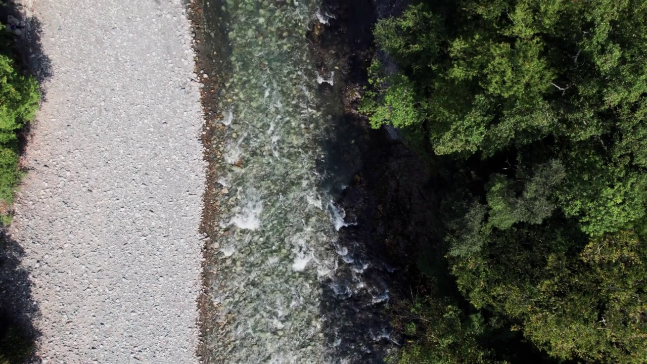 山间翡翠河，石质海岸和森林，溪流湍急，蜿蜒着晶莹剔透的山河。夏日阳光明媚的日子，无人机从上到下的视角视频素材