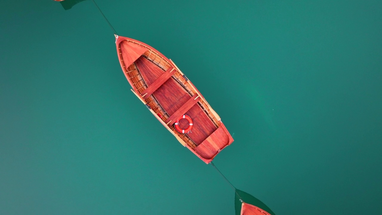 最美丽的布拉斯湖(Lago di Braies)也被称为Pragser Wildsee。白云石山脉,意大利。飞过碧绿平静的水面，小船在一片生涩。视频素材