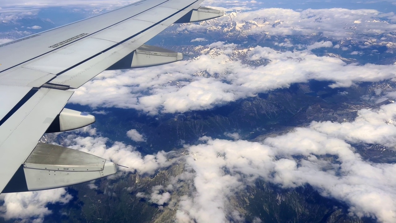 空客A320飞机机翼在阿尔卑斯山脉上空的蓝天上飞行的乘客视角。旅游和航空运输的概念视频素材