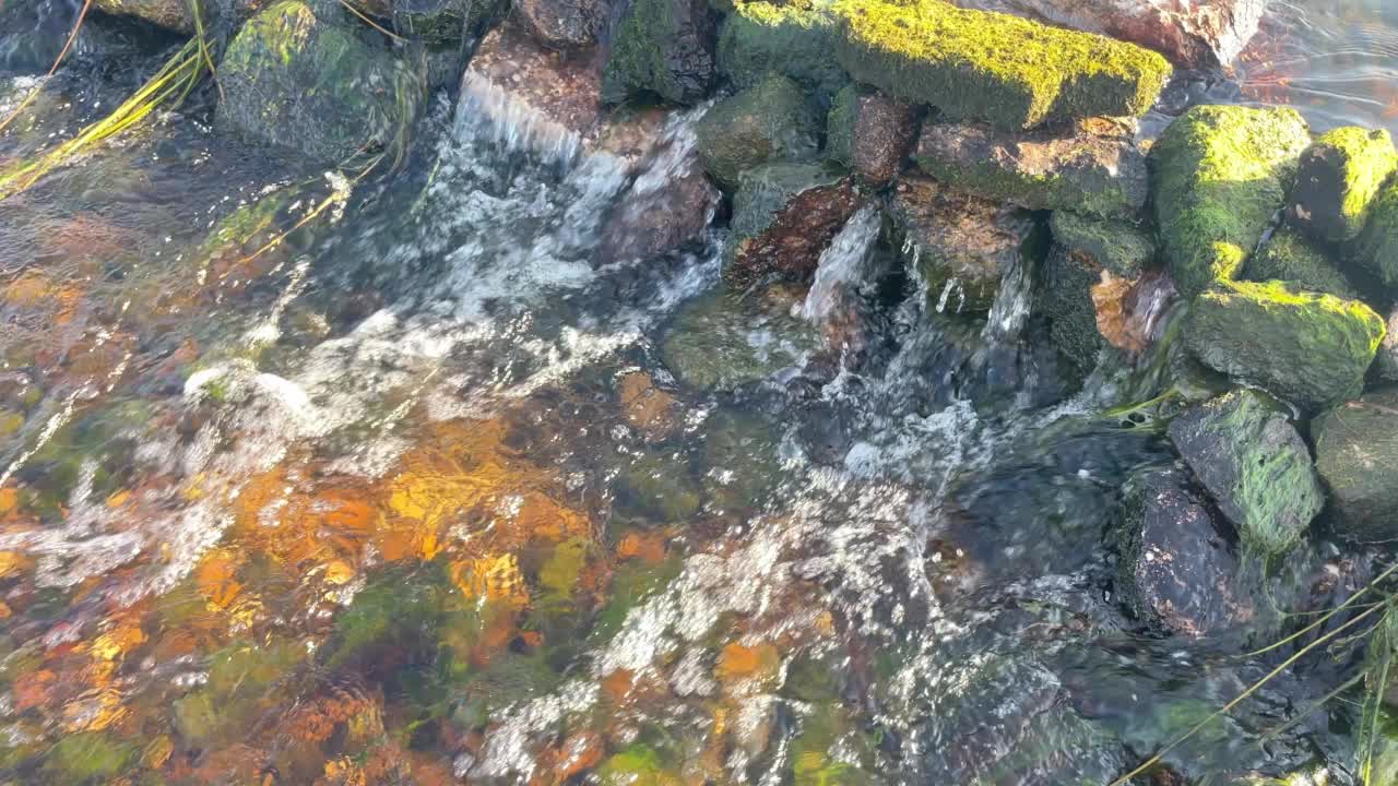 山上流水的美景。小瀑布在山上飞溅。近景，大量的水流落在河岸附近的慢动作。视频素材