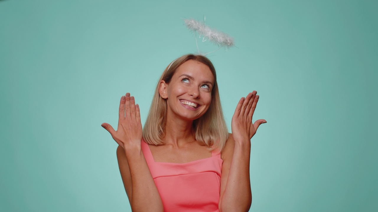 微笑积极害羞的天使女人与天使光环nimb在头顶调情，看着相机视频素材