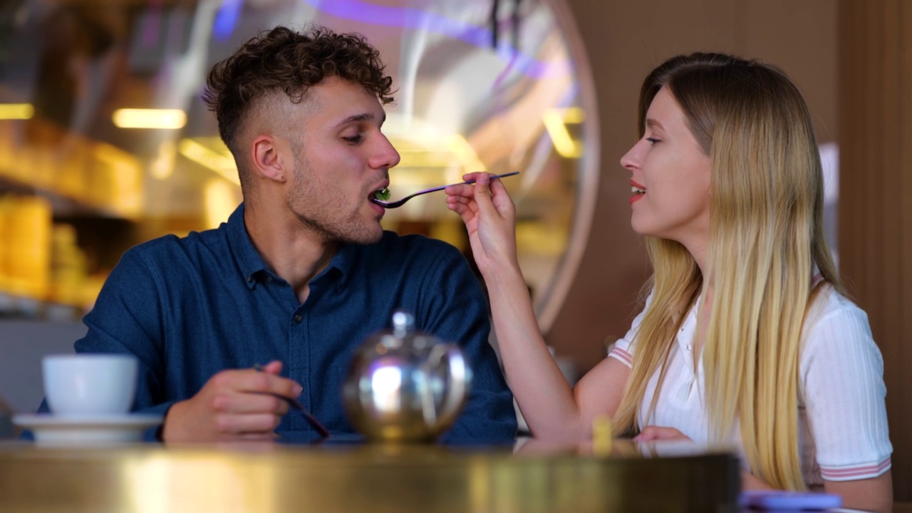 白人青年男女在餐厅里微笑吃饭的特写镜头。快乐的男女朋友一起在自助餐厅进行浪漫的约会。约会。慢动作视频素材