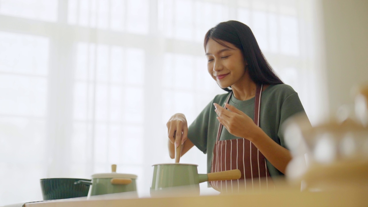 年轻美丽的亚洲妇女做饭在厨房房间在家里视频素材