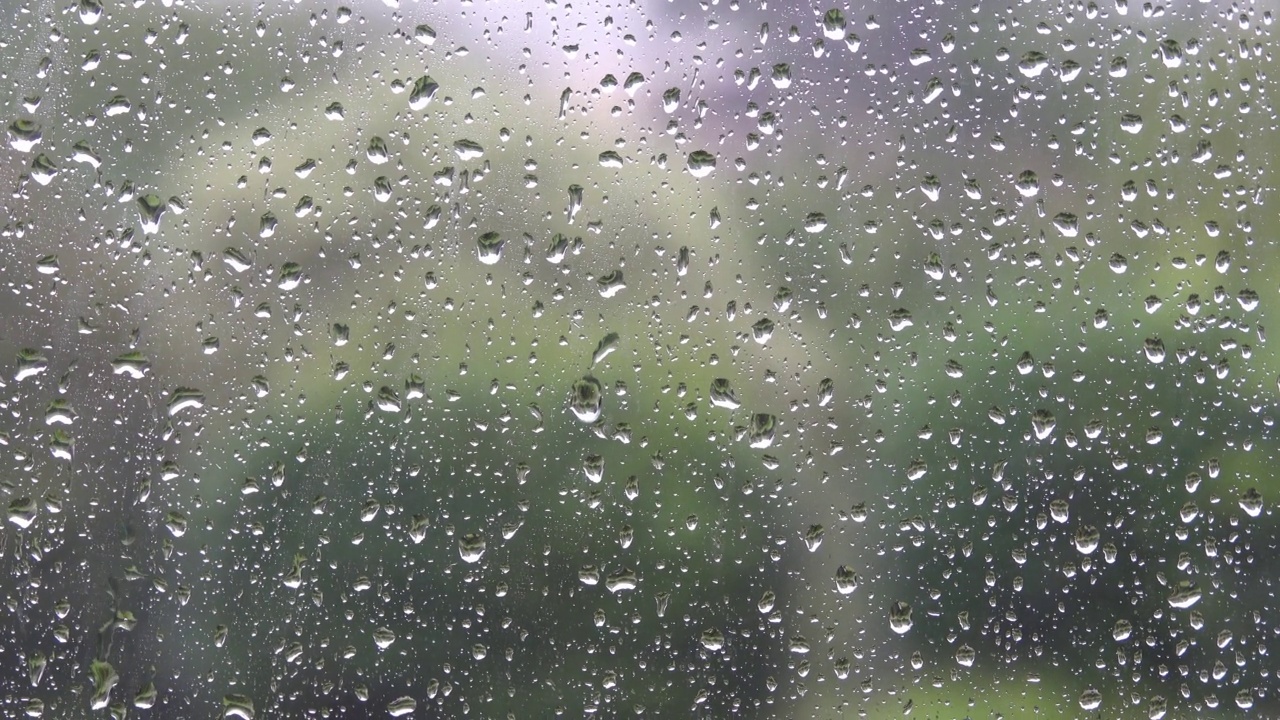 玻璃的背景被大雨的雨滴覆盖。视频素材