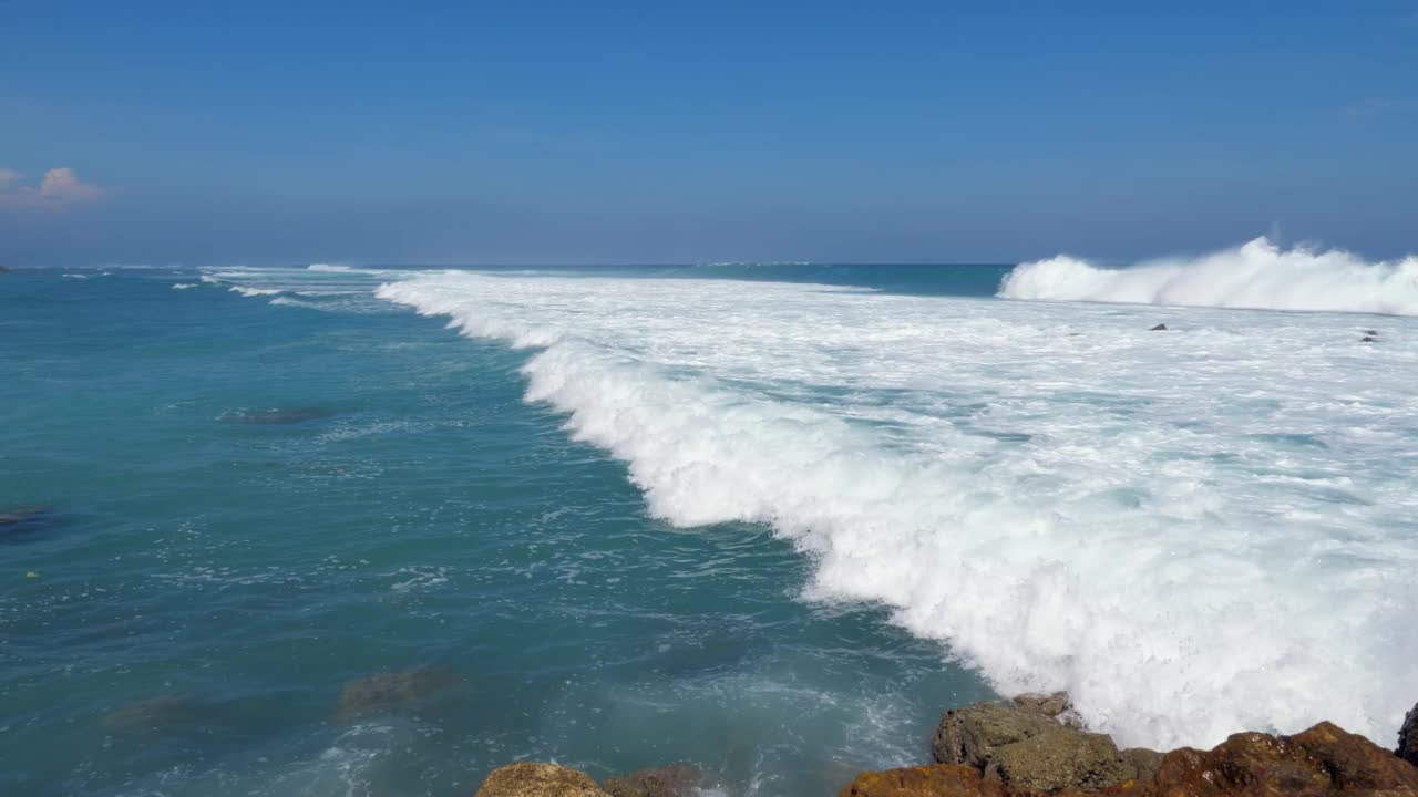 远处海浪拍打，白色的水向岸边流去，广角镜头视频素材