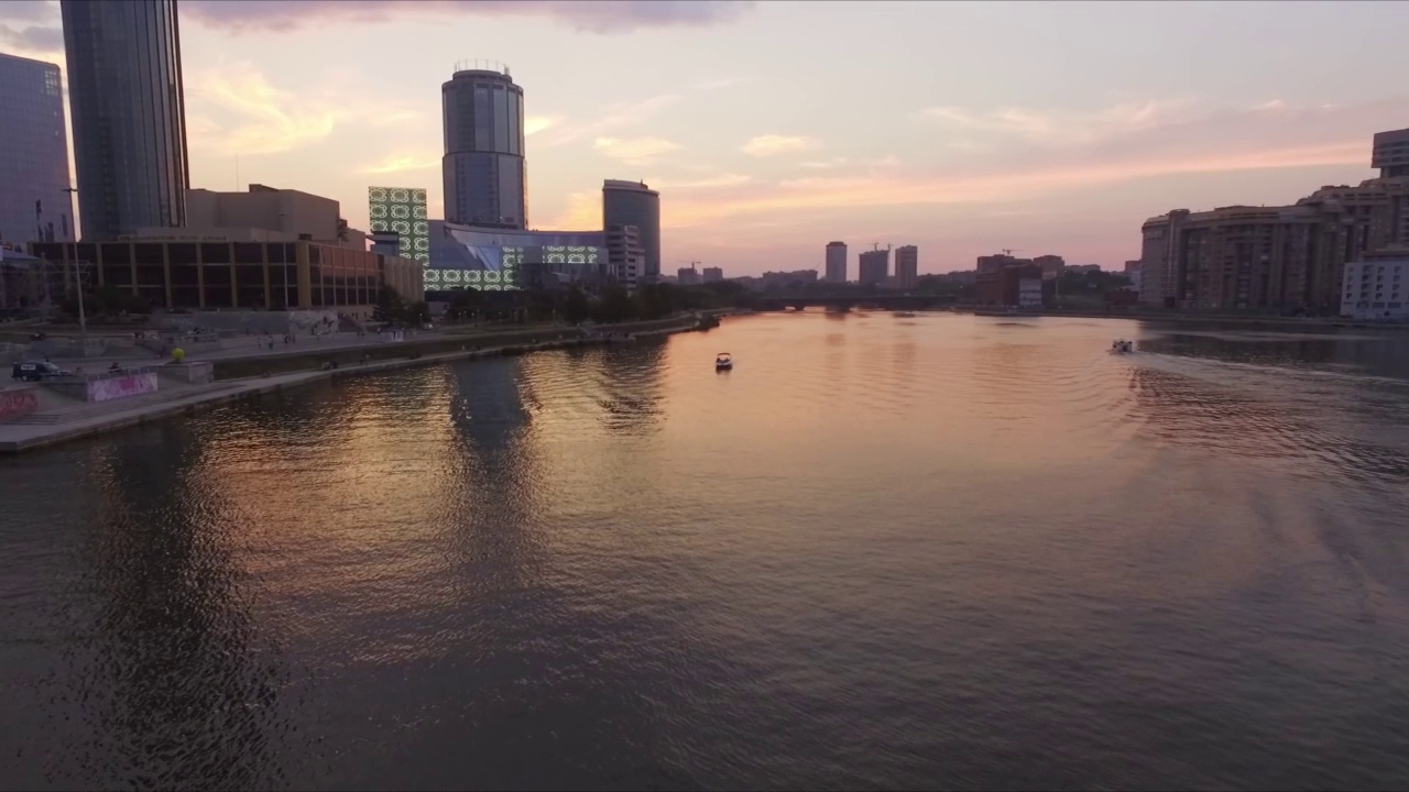 日落时，天空映衬下城市中的河流和船只的航拍视频下载