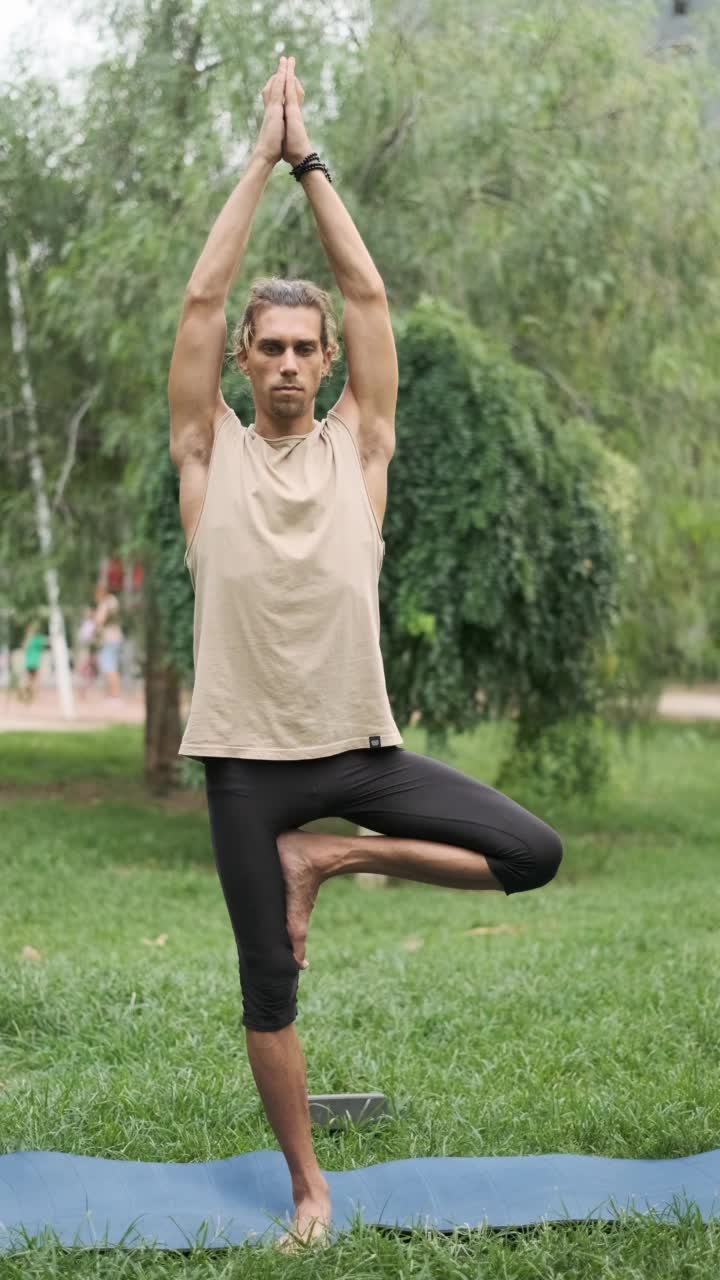 一名男子站在瑜伽垫上，用一只脚保持平衡。视频素材