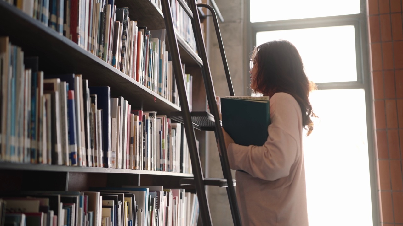 亚洲女学生站在楼梯上一排排书架前视频素材