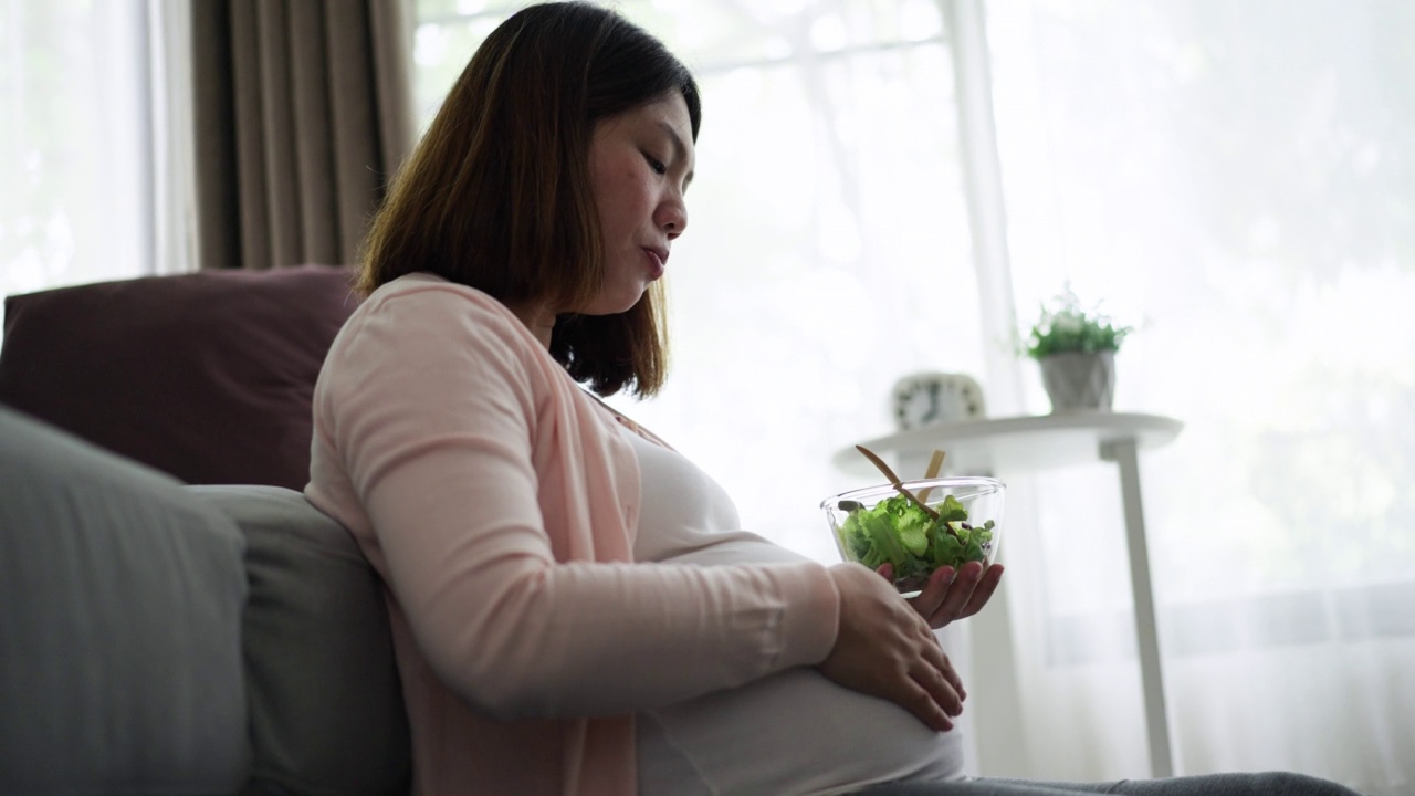 孕妇在家休息，在客厅沙发上吃早餐视频素材