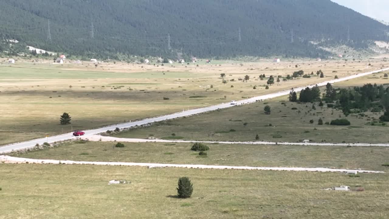 在美丽的阳光明媚的夏天，在美丽的绿色田野中的道路鸟瞰图。五颜六色的风景，路上有汽车。视频素材