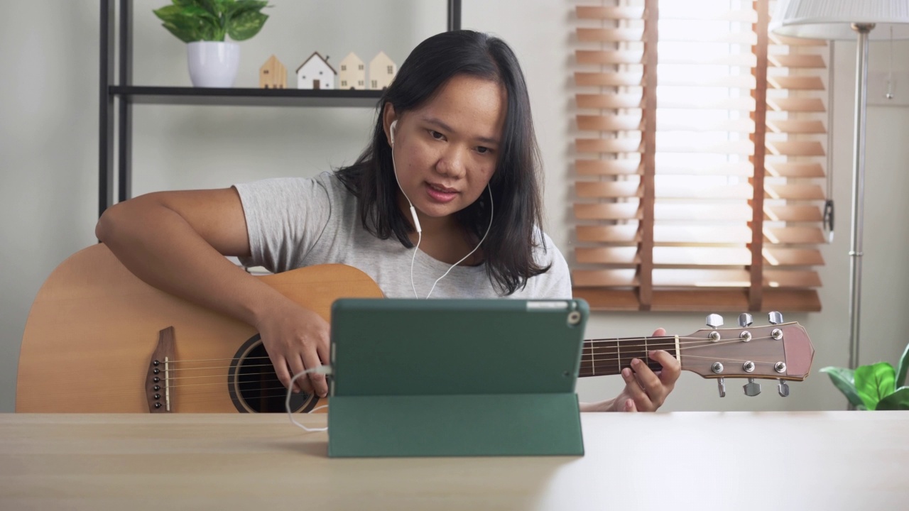 亚洲妇女练习弹原声吉他学习在线教程在家里。以技能提升为理念的周末活动视频素材