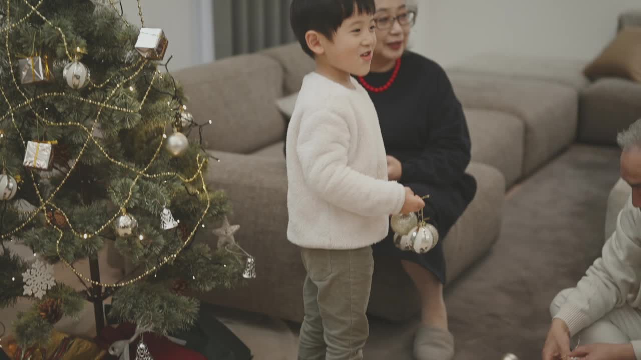 小男孩和他的家人一起装饰圣诞树。视频素材