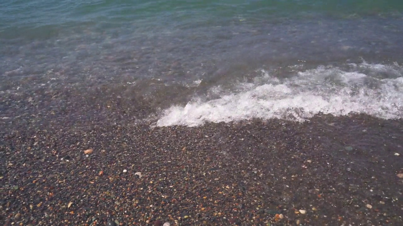 清澈的海水沿着卵石滩的海岸流动视频素材