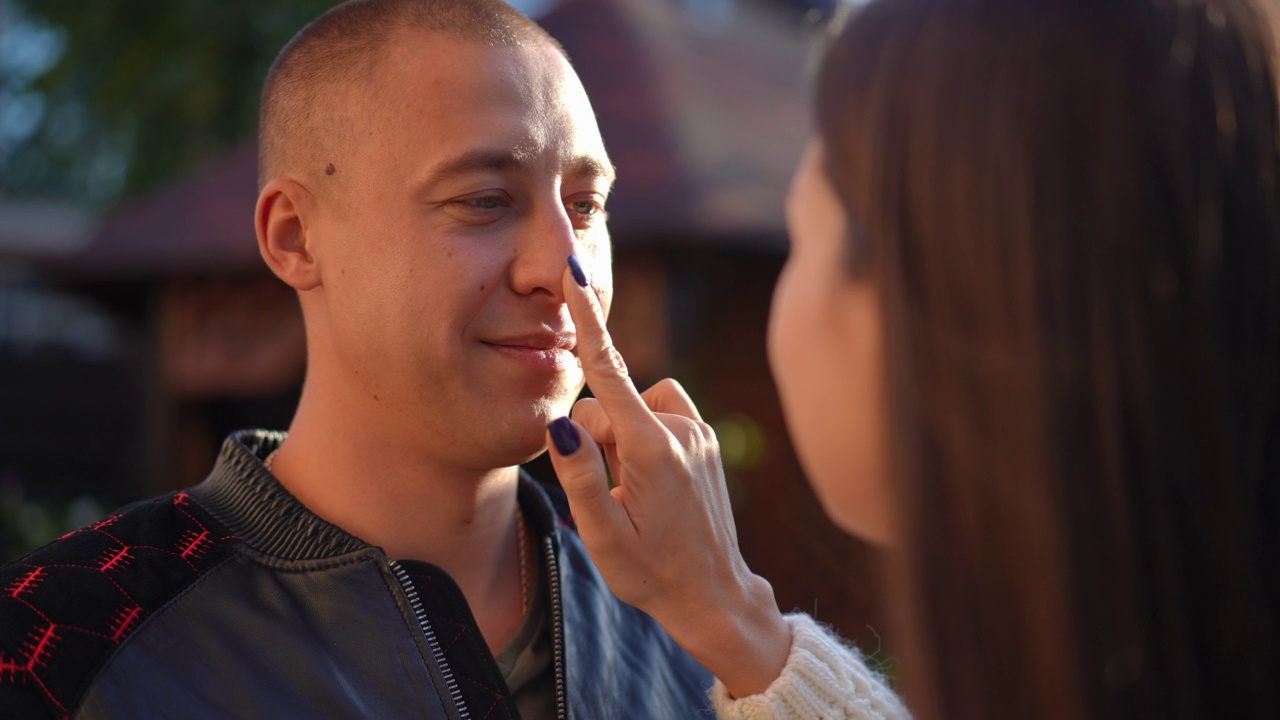 特写微笑爱的男人欣赏女人触摸亲吻的鼻子在慢动作。在阳光明媚的日子里，白人浪漫男友和女友在户外约会。幸福和关系。视频素材