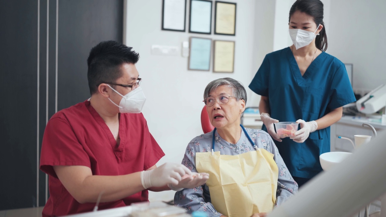 亚裔华人男牙医向年长妇女展示假牙安装程序视频素材