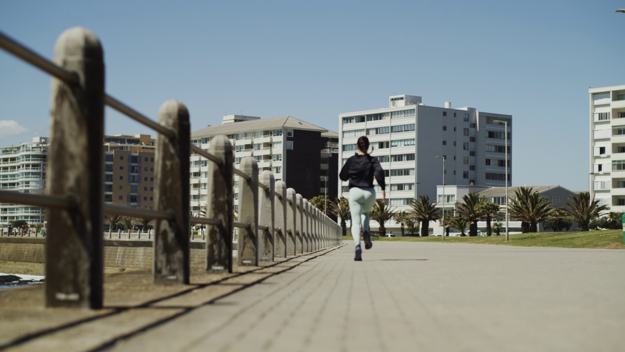 一个健康的年轻女子从后面跑和慢跑在散步在城市的户外城市。女运动员做早上的有氧运动和锻炼更好的健康和健身视频素材