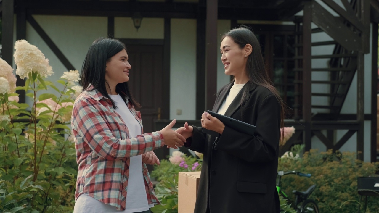 一名白人妇女与一名亚洲房地产经纪人签订了数字合同。视频素材
