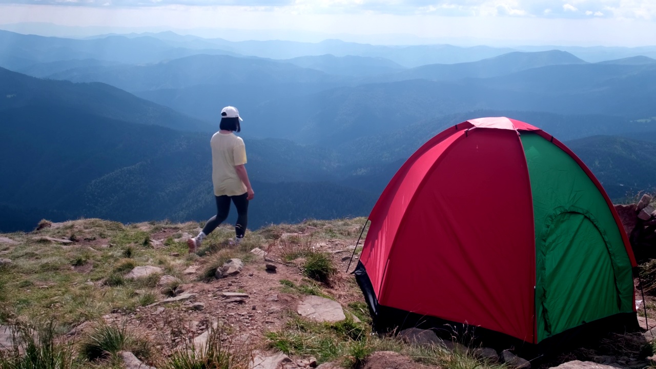 悬崖上搭帐篷的女人在欣赏山景视频素材