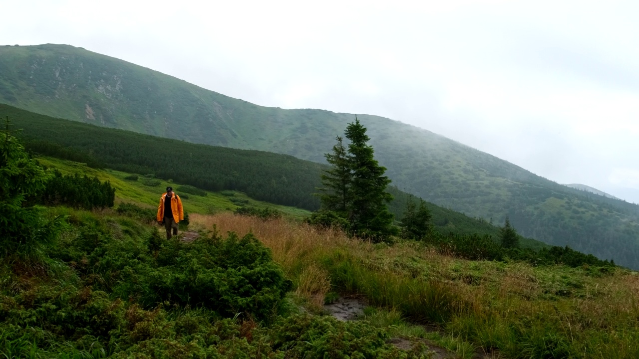 穿黄雨衣的人走在山路上视频素材