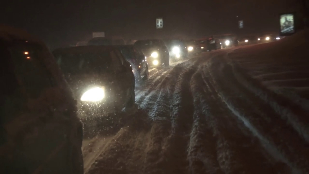 在冬夜的暴风雪中，汽车堵塞了交通视频素材