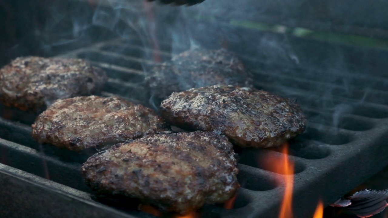 厨师用火钳烤汉堡肉饼。做汉堡的肉是煮好的视频素材