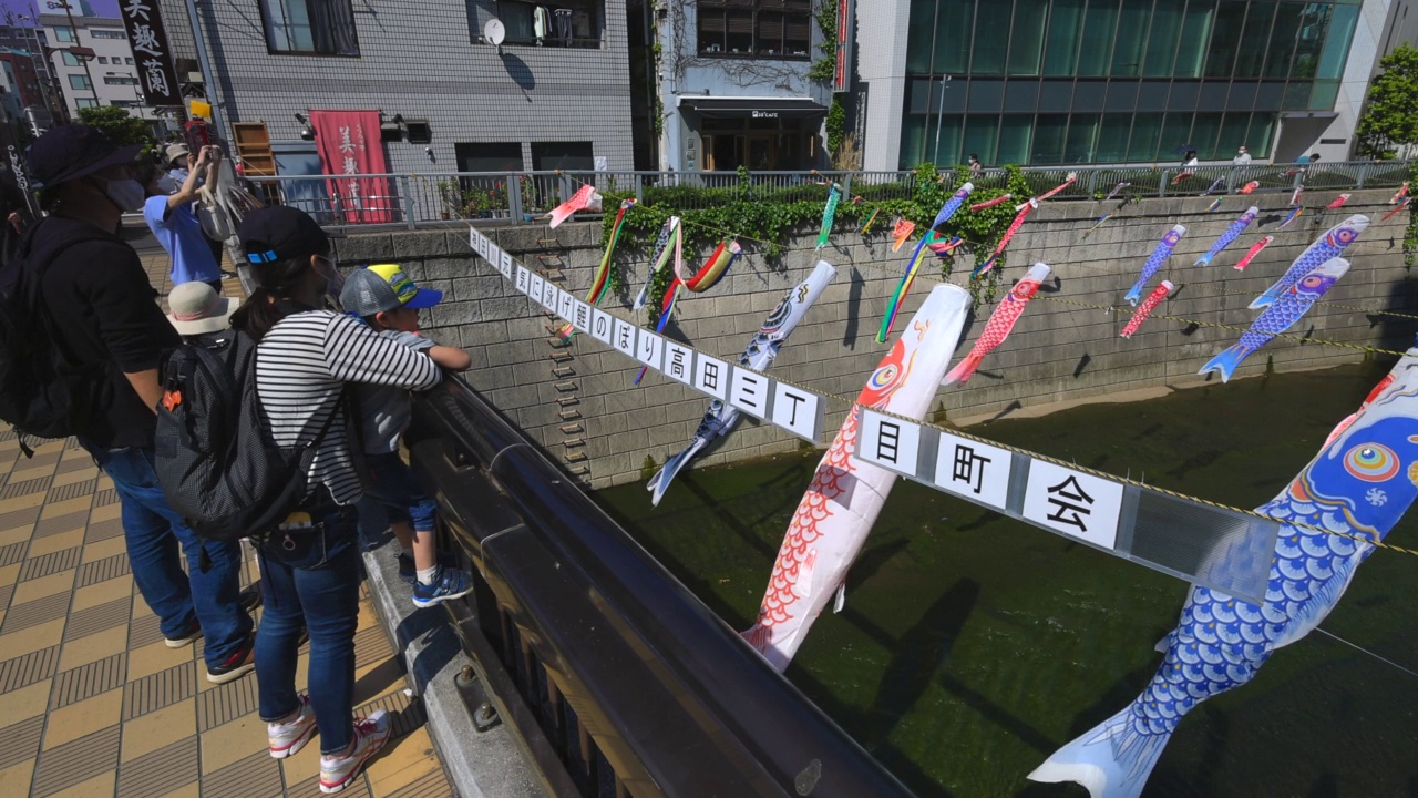 在日本东京新宿高田桥的儿童节，小inobori鲤鱼飘带在风中飘过神田河视频素材