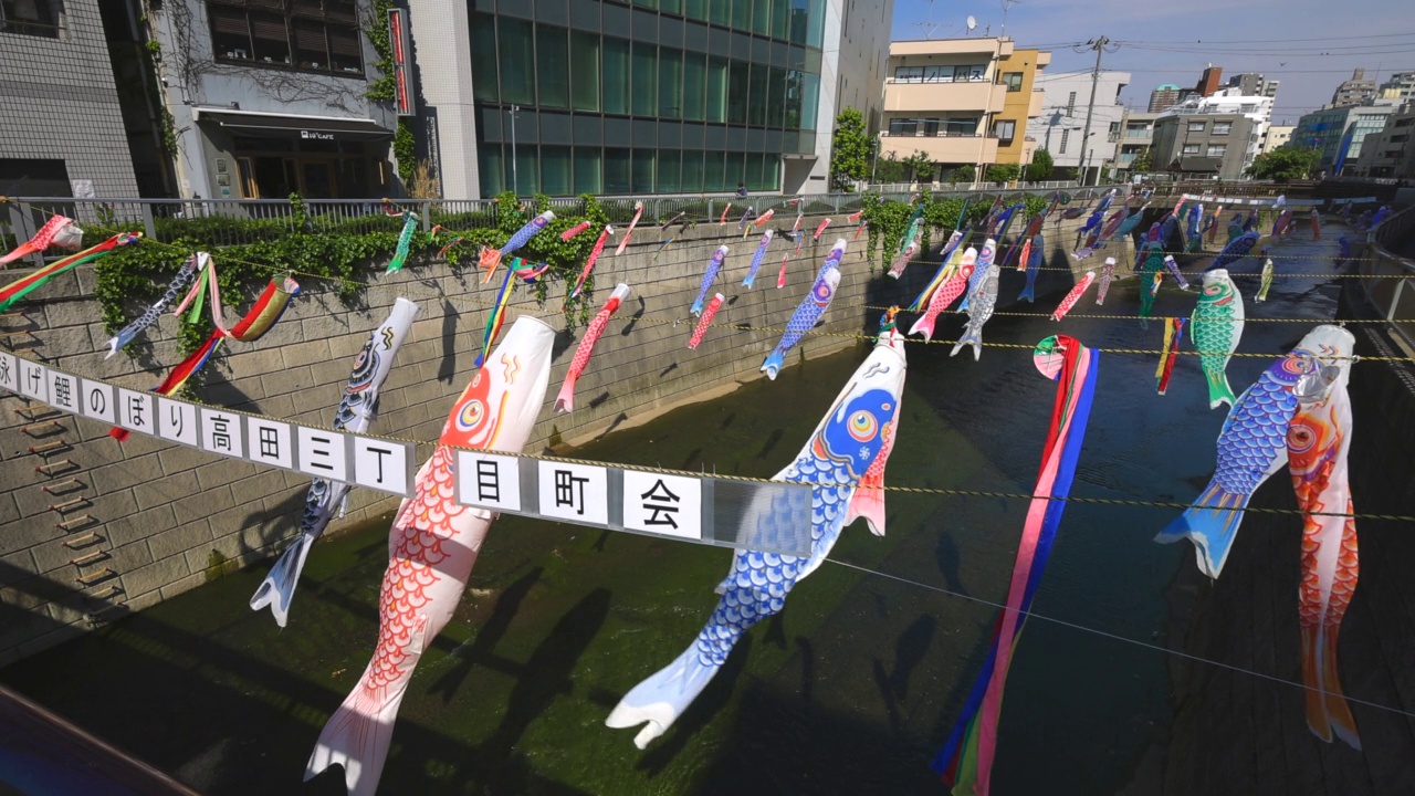 在日本东京新宿高田桥的儿童节，小inobori鲤鱼飘带在风中飘过神田河视频素材